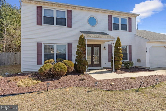 view of front of home featuring french doors, an attached garage, and fence