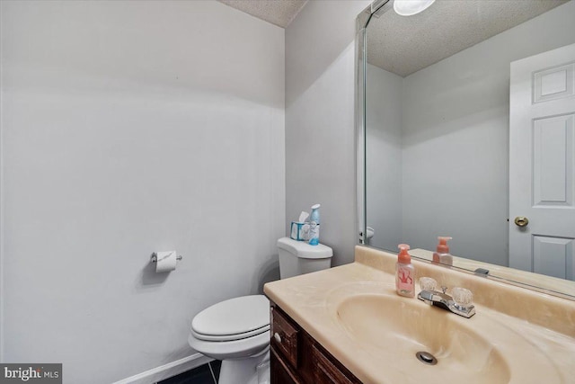 bathroom featuring a textured ceiling, vanity, toilet, and baseboards