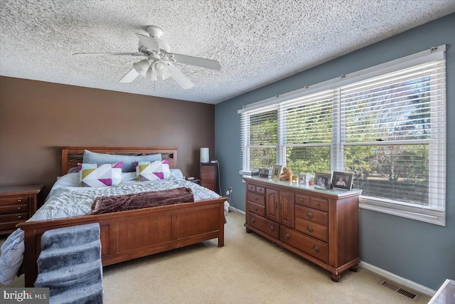 bedroom featuring ceiling fan, a textured ceiling, light carpet, visible vents, and baseboards