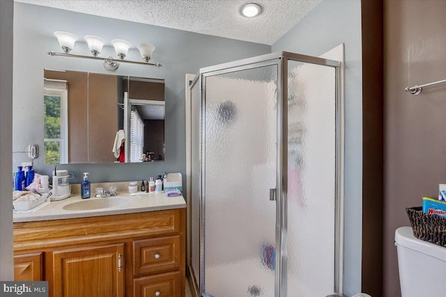 full bath featuring toilet, a stall shower, a textured ceiling, and vanity