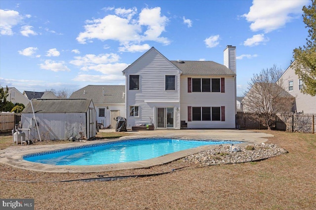 exterior space featuring a fenced backyard, a chimney, a storage unit, an outdoor structure, and a patio area