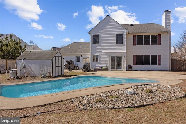 view of pool featuring an outbuilding, fence, a fenced in pool, a storage unit, and a patio area