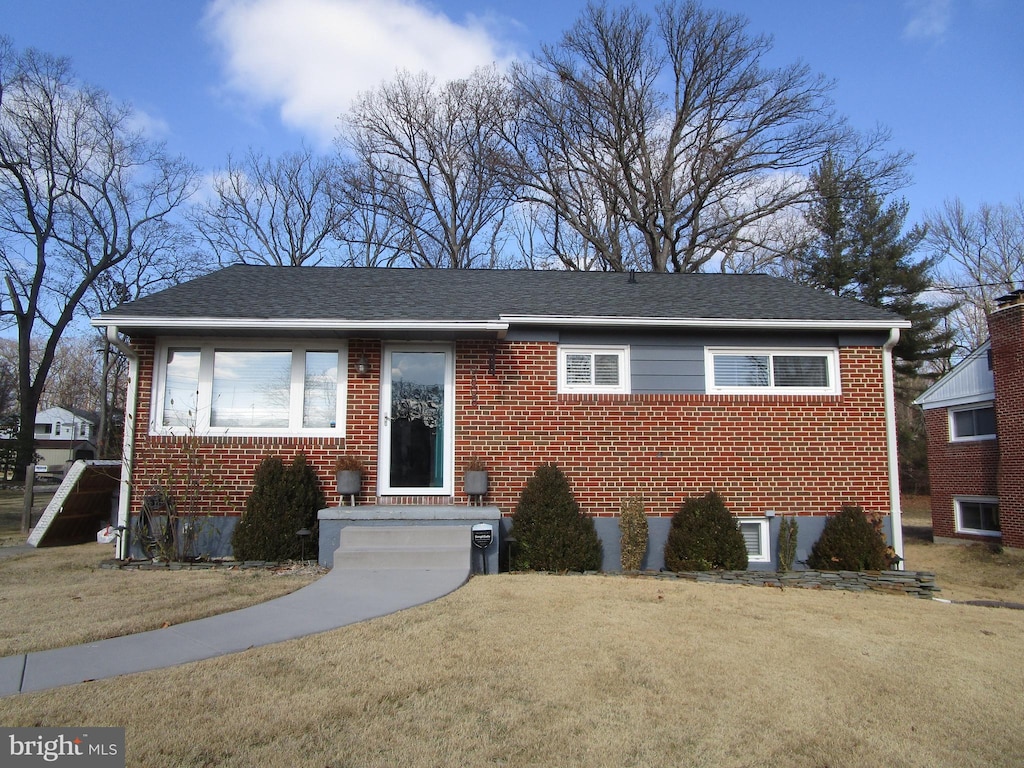 bungalow-style house featuring brick siding, a front yard, and roof with shingles