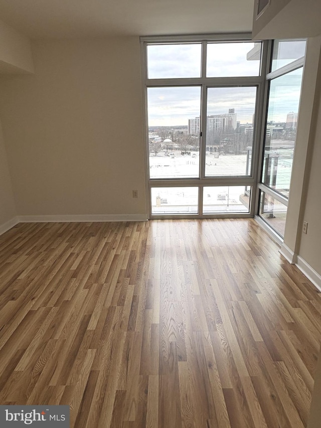 empty room with baseboards, a view of city, and wood finished floors