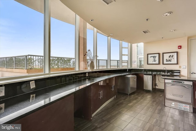 kitchen featuring visible vents, dark brown cabinets, a sink, and dark tile patterned flooring