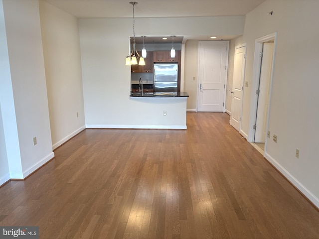 unfurnished living room featuring dark wood finished floors, baseboards, and a sink