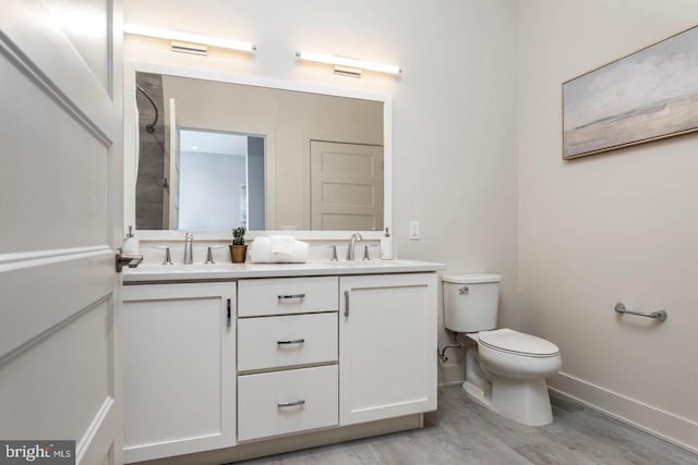 full bathroom with double vanity, toilet, baseboards, and a sink