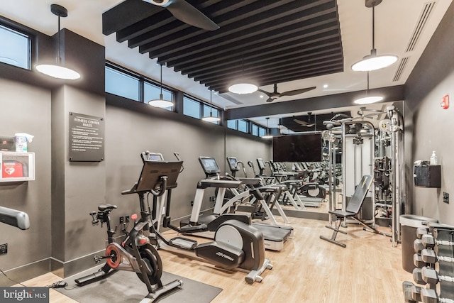 workout area with baseboards, wood finished floors, visible vents, and ceiling fan