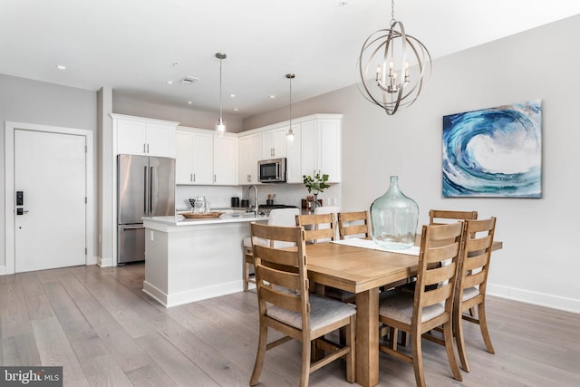 dining area with recessed lighting, baseboards, an inviting chandelier, and light wood-style flooring