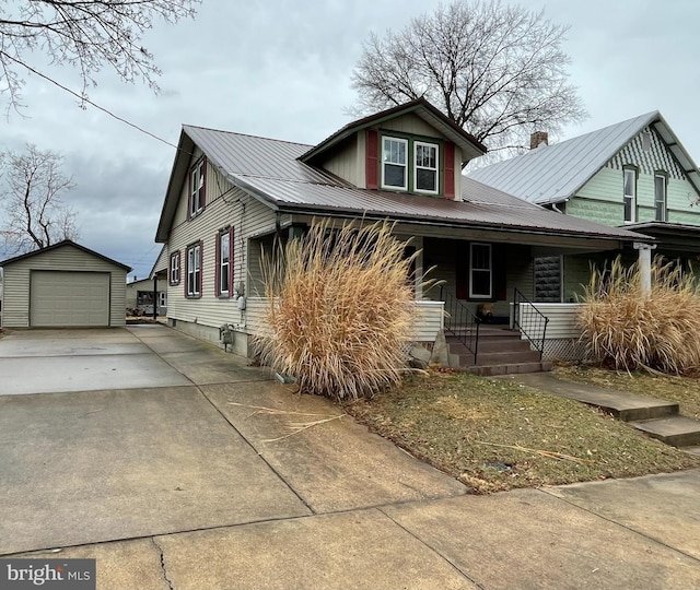 view of front of home featuring driveway, a porch, an outdoor structure, a garage, and metal roof