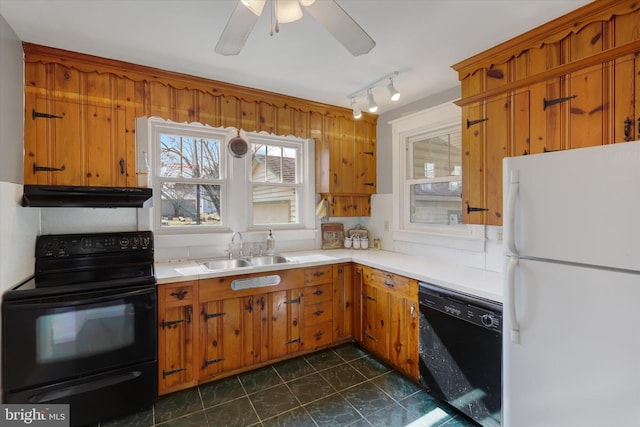 kitchen with brown cabinetry, a sink, black appliances, light countertops, and under cabinet range hood