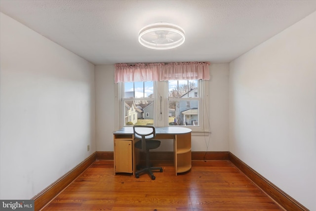 office with baseboards, a textured ceiling, and light wood finished floors