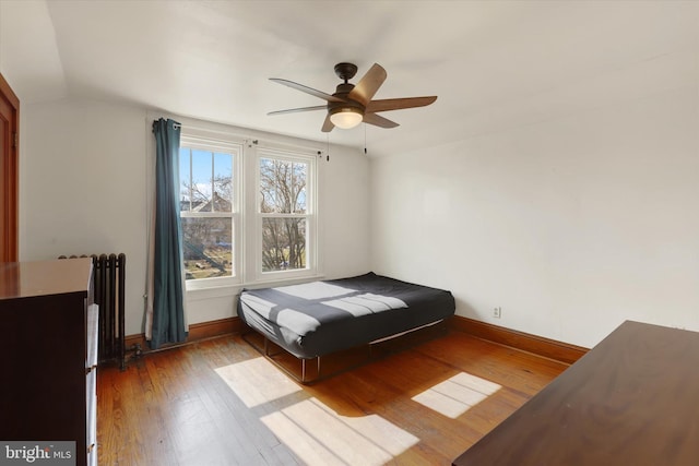 bedroom with ceiling fan, baseboards, radiator heating unit, lofted ceiling, and hardwood / wood-style flooring