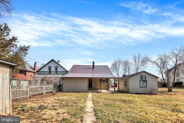 rear view of property with metal roof, a patio area, a lawn, and fence