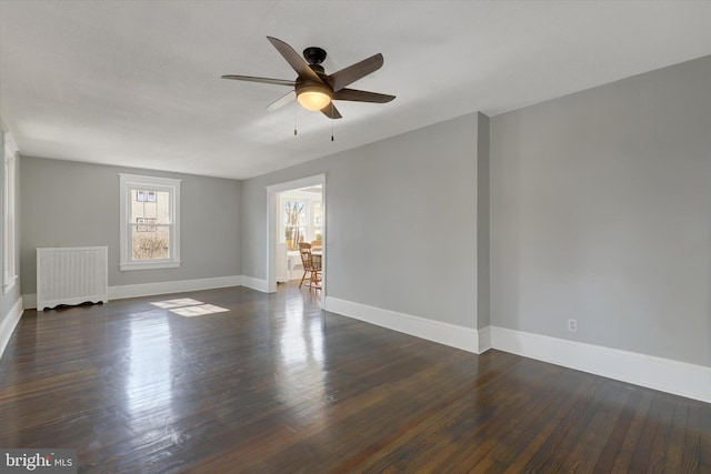 unfurnished room with radiator, baseboards, dark wood-type flooring, and a ceiling fan