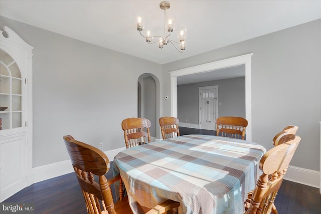 dining space with baseboards, arched walkways, a notable chandelier, and wood finished floors