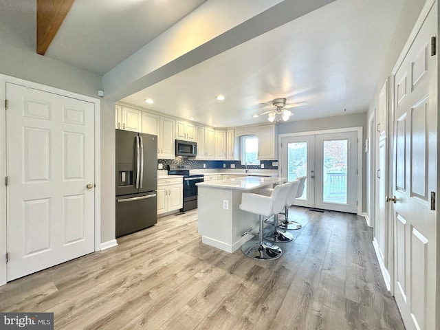 kitchen featuring french doors, light countertops, decorative backsplash, appliances with stainless steel finishes, and light wood-style floors