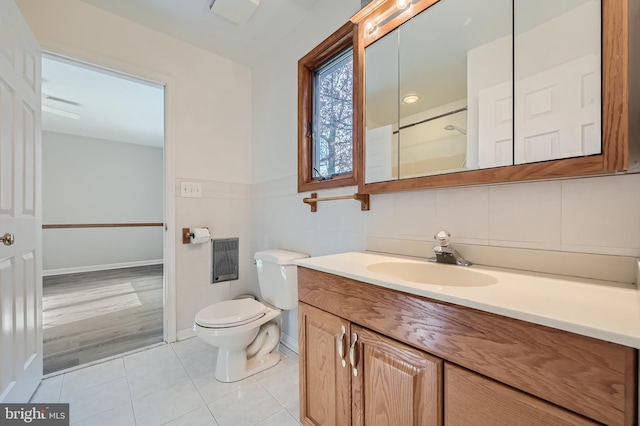 bathroom with toilet, tile patterned flooring, tile walls, and vanity