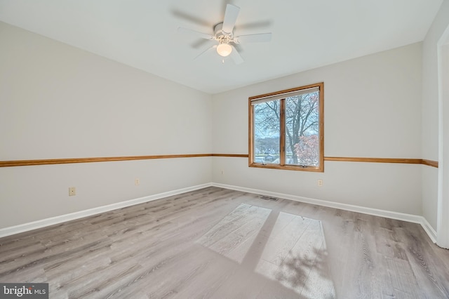 unfurnished room featuring a ceiling fan, visible vents, baseboards, and wood finished floors