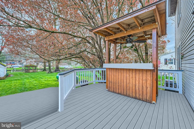 deck featuring ceiling fan and a yard