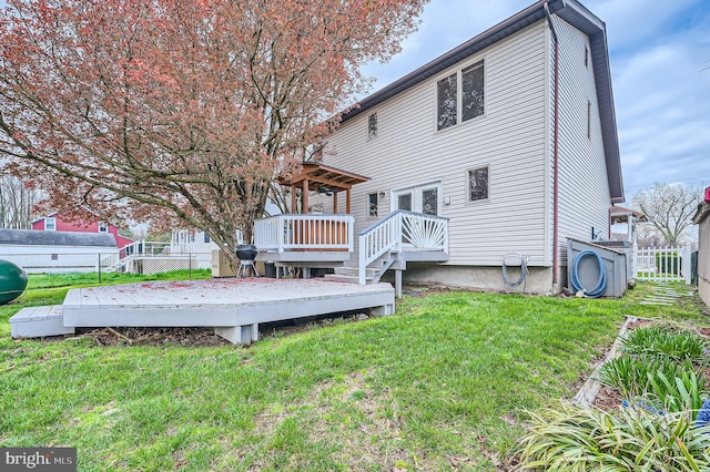 back of property featuring a deck, a lawn, and fence