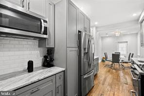 kitchen with appliances with stainless steel finishes, gray cabinets, decorative backsplash, and light countertops