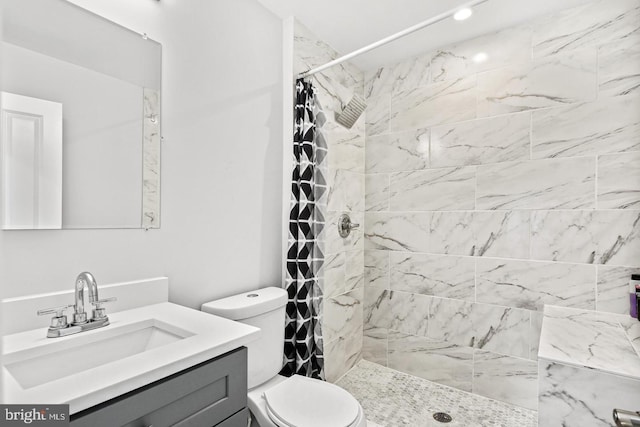 bathroom featuring toilet, tiled shower, and vanity