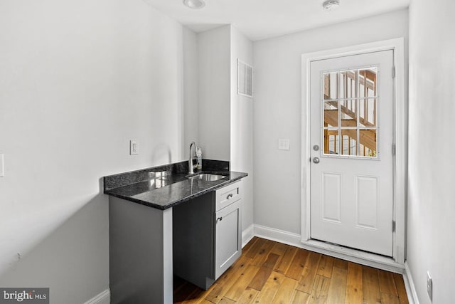 bar with light wood-style floors, visible vents, a sink, and baseboards