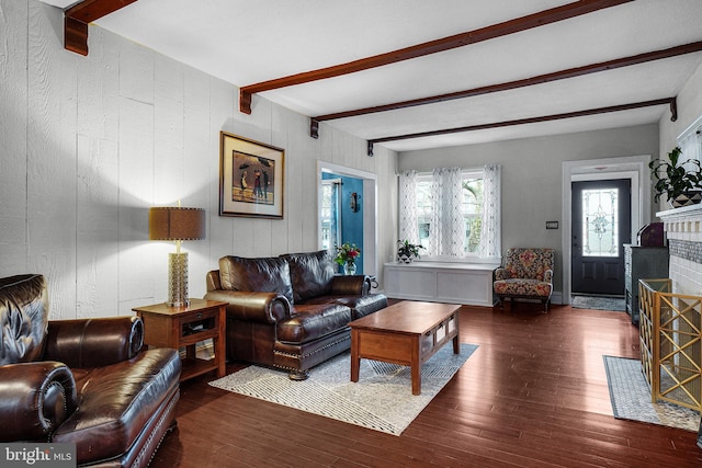 living area featuring beamed ceiling, a brick fireplace, and hardwood / wood-style floors