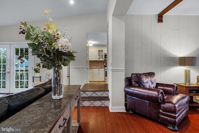 living room featuring french doors, beamed ceiling, dark wood-style floors, and wood walls