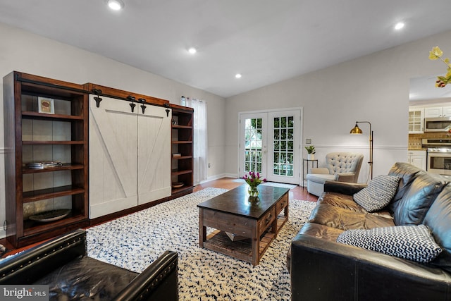 living area with wood finished floors, lofted ceiling, recessed lighting, french doors, and a barn door