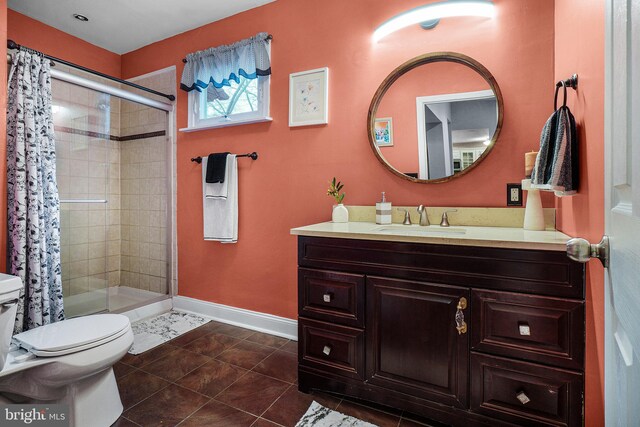 full bath featuring vanity, baseboards, tiled shower, tile patterned flooring, and toilet