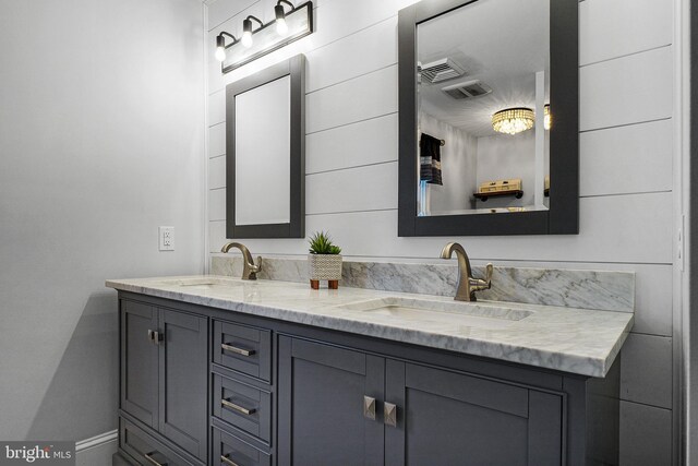 full bath with double vanity, baseboards, visible vents, and a sink