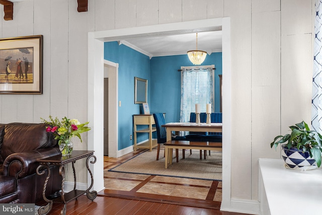 dining room with dark wood-type flooring, a notable chandelier, baseboards, and ornamental molding