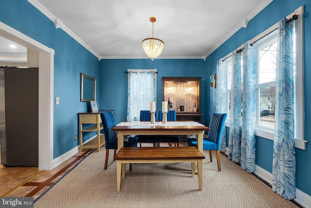 dining room with an inviting chandelier, crown molding, and baseboards