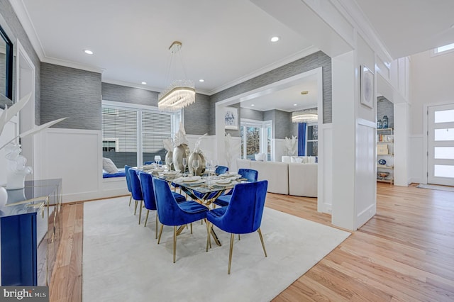 dining space featuring a decorative wall, wainscoting, crown molding, and wood finished floors