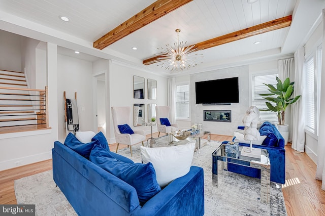 living room with beam ceiling, a notable chandelier, wood finished floors, stairway, and baseboards