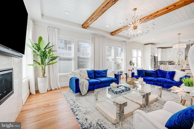 living room featuring a chandelier, light wood-type flooring, a premium fireplace, beam ceiling, and wooden ceiling