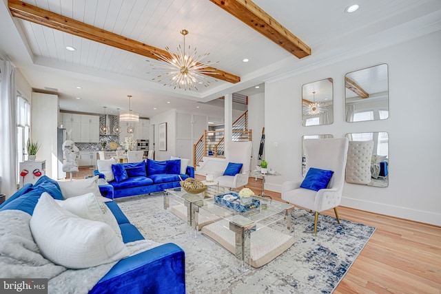 living area with beam ceiling, wood finished floors, stairway, an inviting chandelier, and baseboards