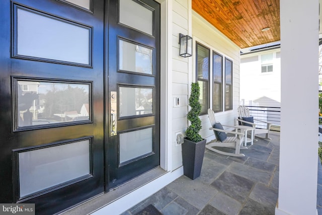 view of exterior entry featuring covered porch and stucco siding