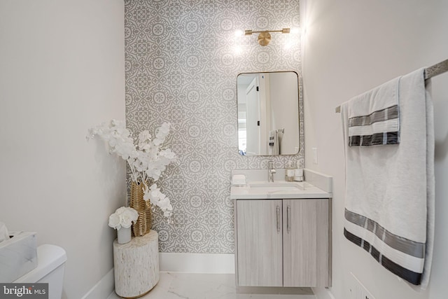 half bathroom with vanity, toilet, and marble finish floor