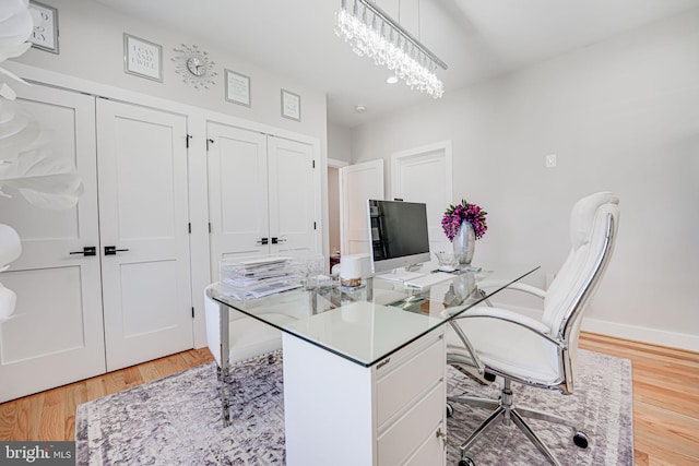 office space with a chandelier, baseboards, and light wood-style floors