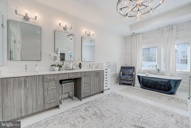 full bath featuring double vanity, a soaking tub, a notable chandelier, and a sink