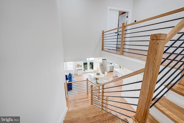 stairs featuring baseboards, wood finished floors, and a towering ceiling