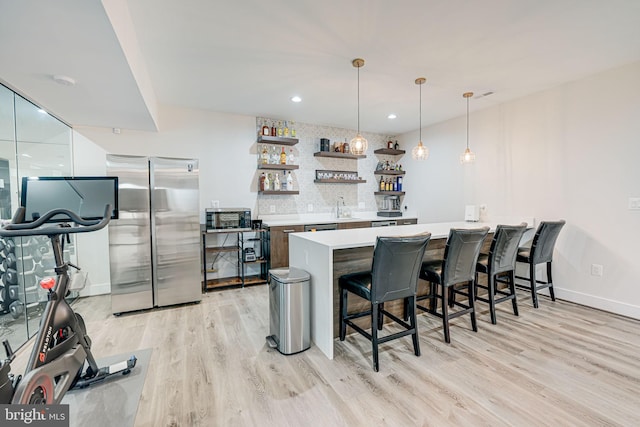 kitchen featuring a breakfast bar area, open shelves, a sink, appliances with stainless steel finishes, and tasteful backsplash