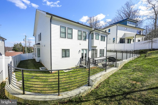 rear view of house with a lawn and a fenced backyard