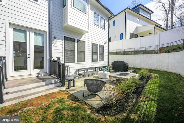 view of patio featuring fence, french doors, and a fire pit