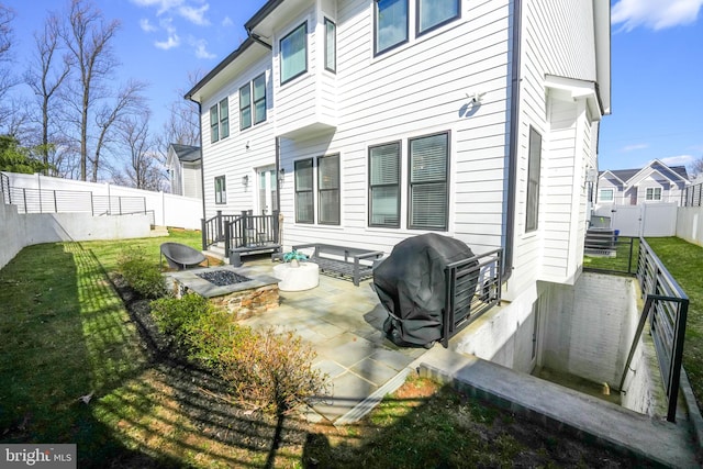 back of house with a patio, a fenced backyard, a lawn, and an outdoor fire pit