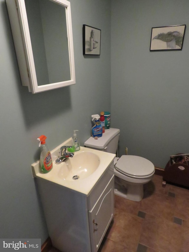 half bathroom with toilet, tile patterned floors, and vanity