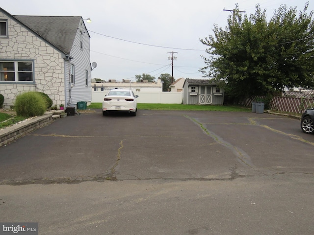 view of car parking with a storage unit and fence